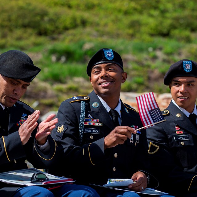 Three US military servicemen holding US flags